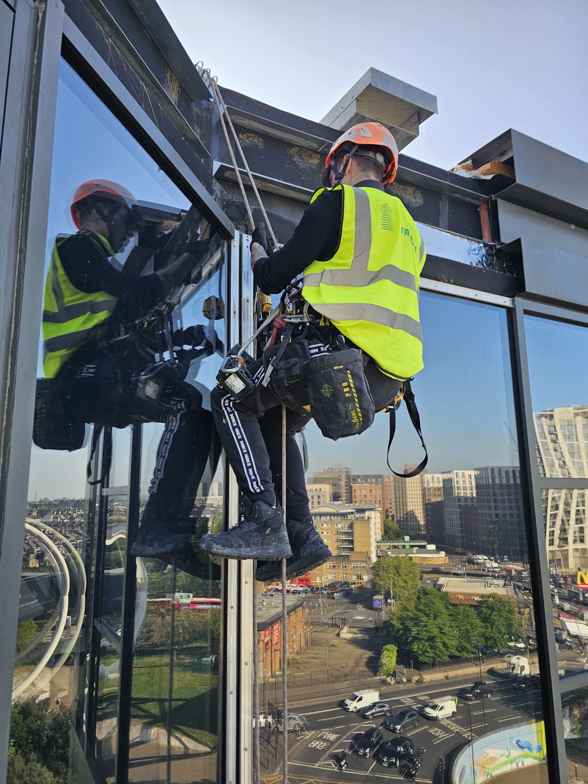 Technicians undertaking controlled rope access tasks on a vertical façade surface.
