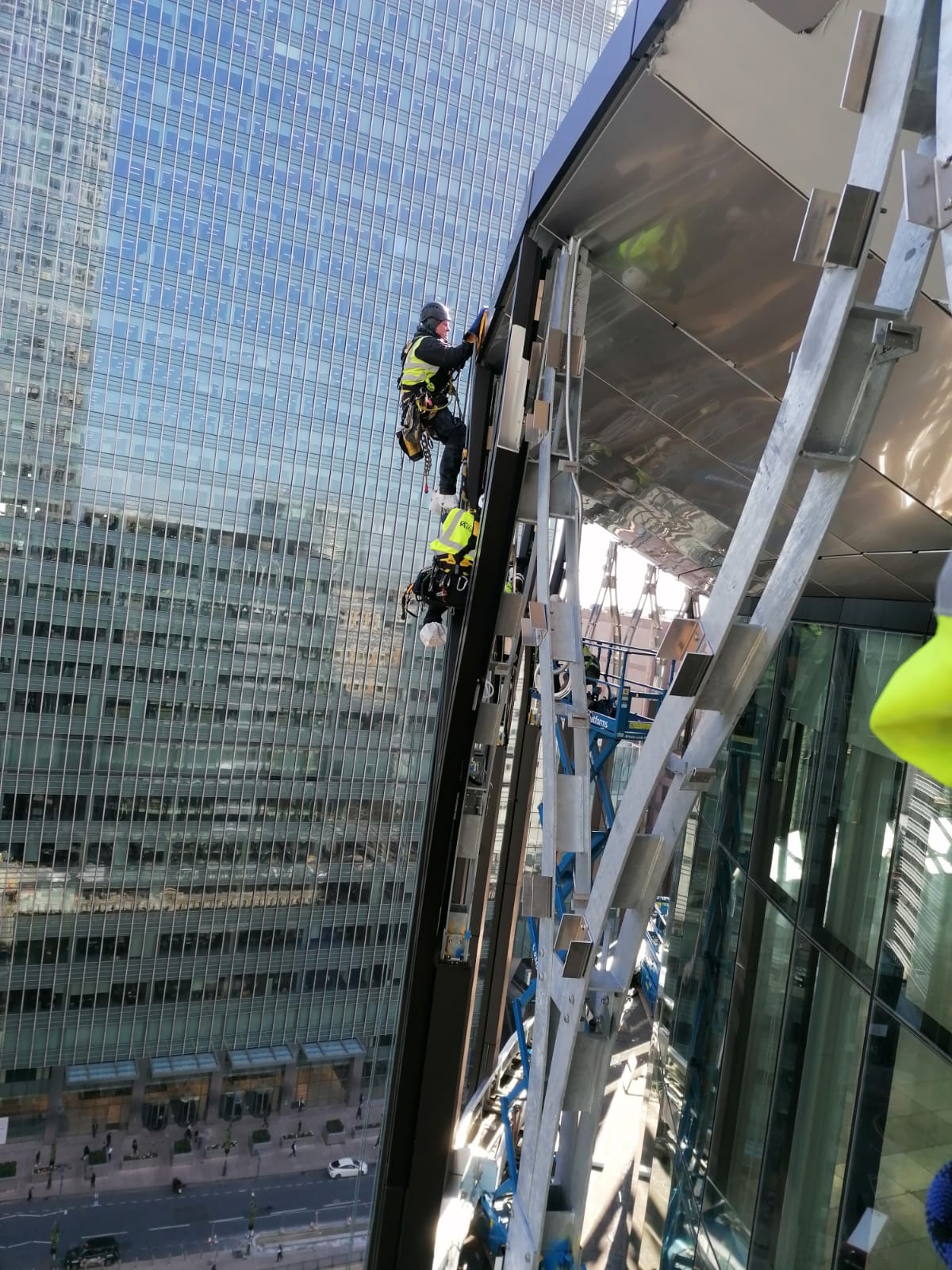 Technicians performing controlled façade access on a high-rise structure overlooking the city.